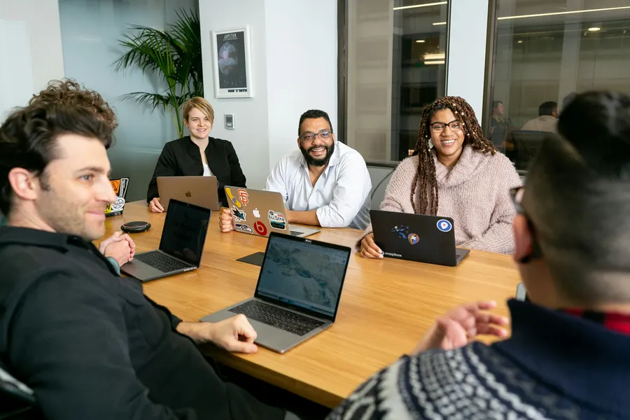 Team arbeitet gemeinsam mit Laptops an einem Tisch