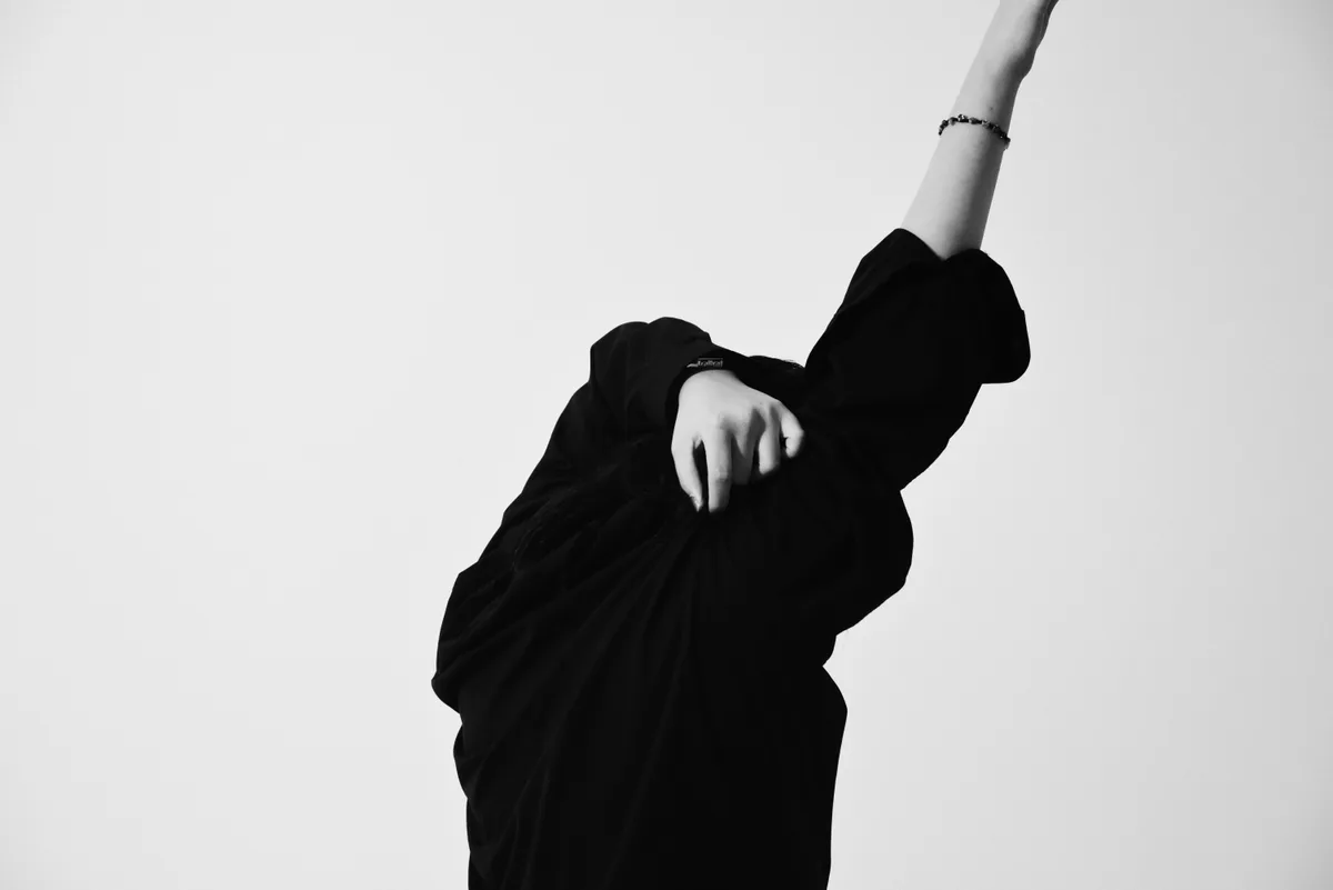 Model in reduziertem, minimalistischem Outfit vor heller Wand